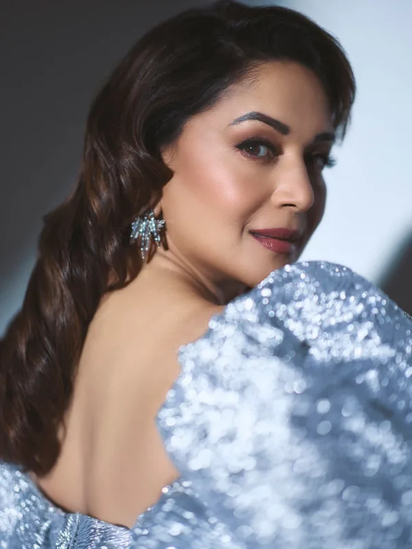 Madhuri Dixit Nene wearing a black evening gown with dramatic metallic ruffle shoulders and statement diamond earrings on the red carpet.